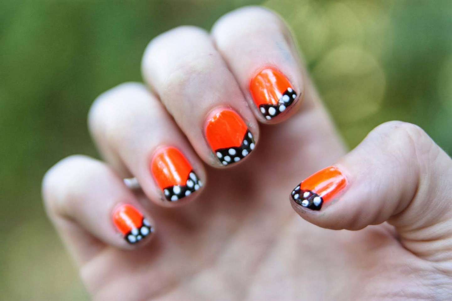 Nail art arancione con pois bianchi