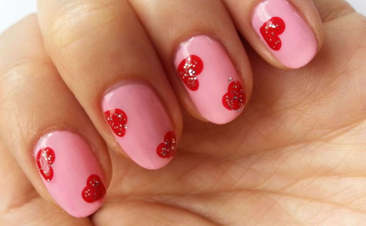 Nail art rosa con cuoricini rossi