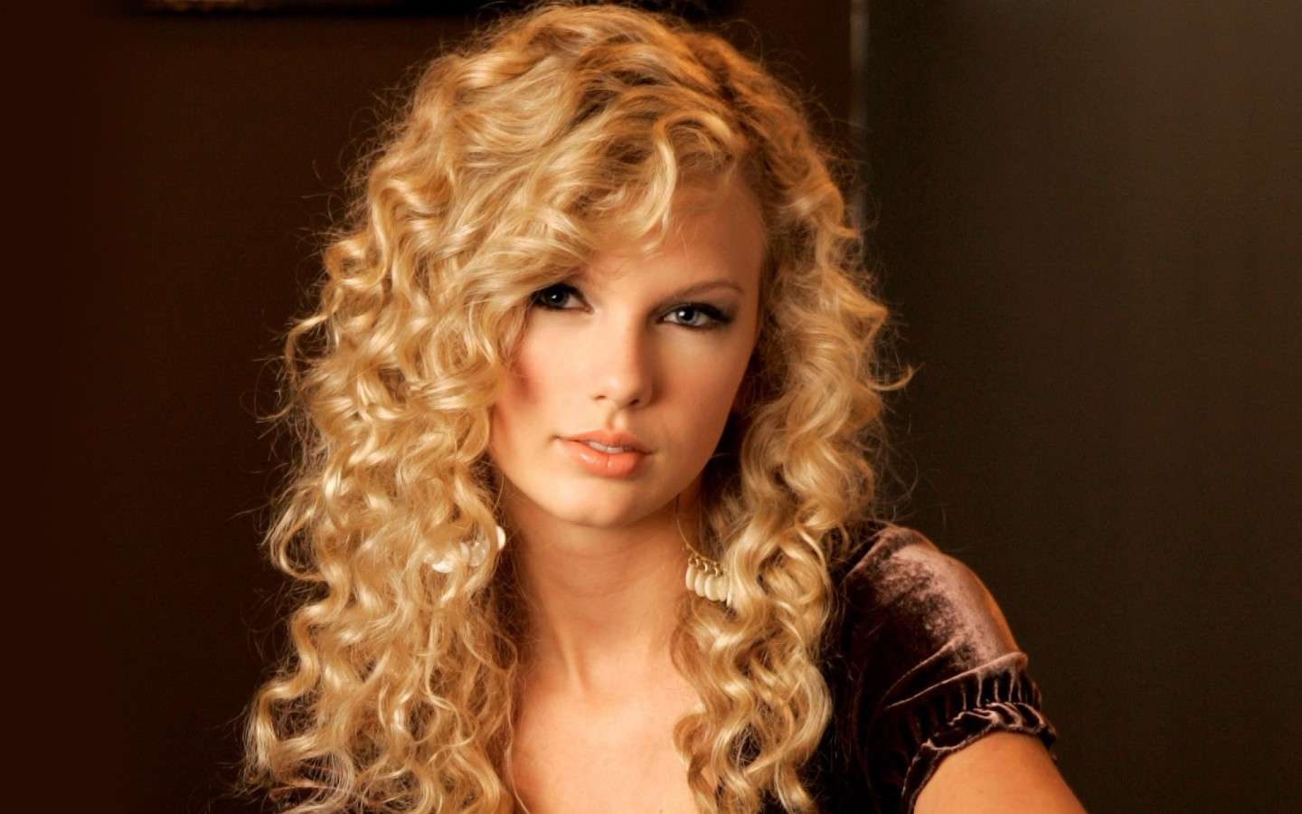 Taylor Swift con ricci lunghi e riga di lato