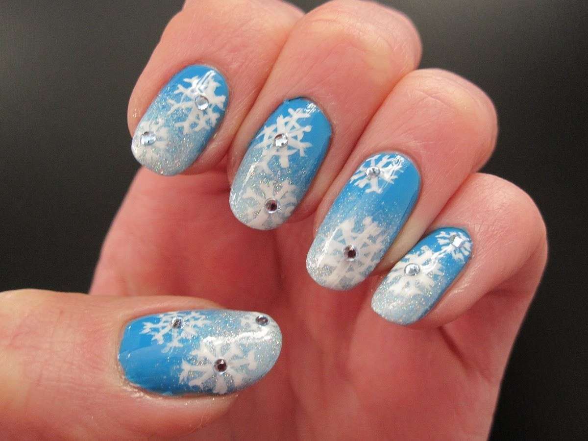 Nail art celeste con fiocchi di neve e strass