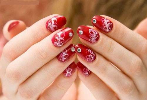 Nail art rossa con decorazioni e strass