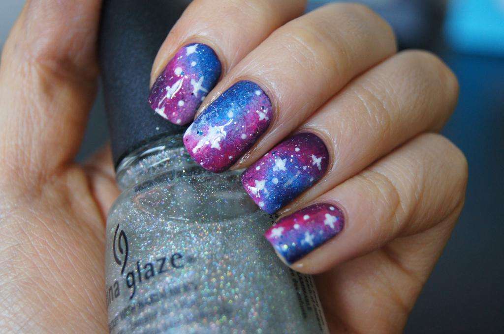 Nail art viola e blu con galassia