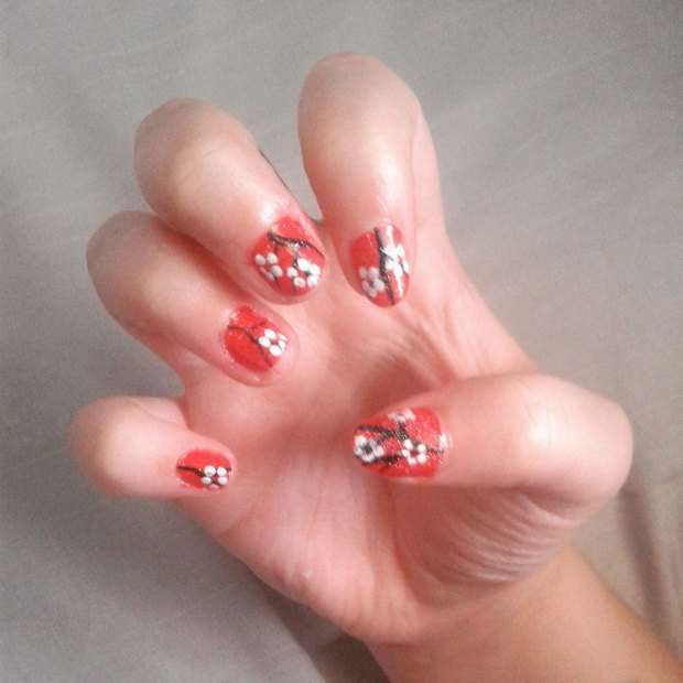 Nail art arancione con fiori di ciliegio